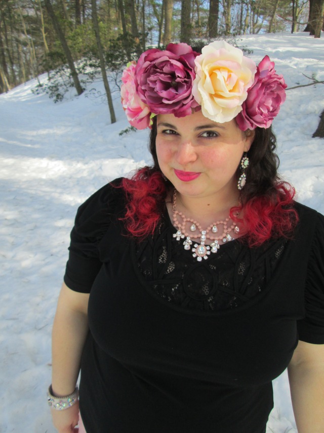 plus size outfit with black top, rhinestone necklace, and giant flower crown