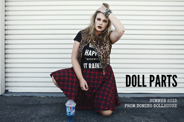 domino dollhouse model wearing "only happy when it rains" t-shirt, red plaid skirt, and leopard vest